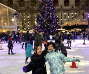 Two young girls pose together on skates, while they enjoy an evening of skating at the ice rink at Bryant Park.