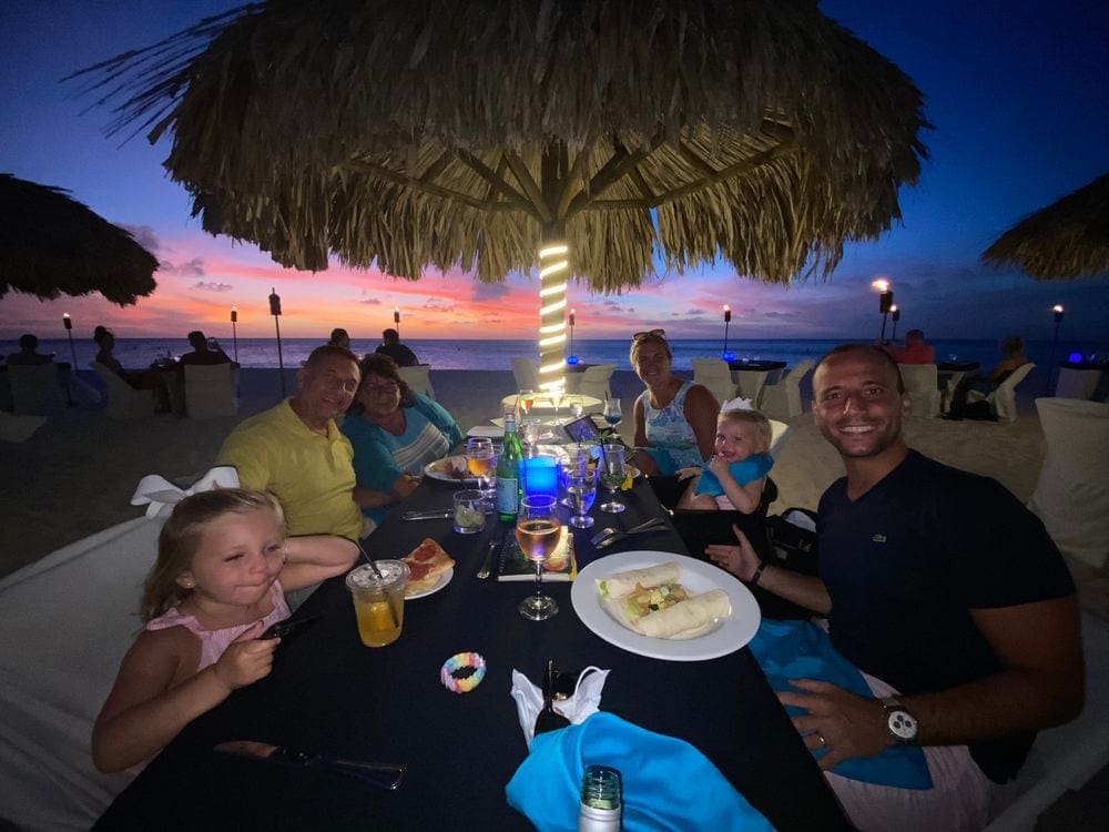 A large family enjoys an evening meal on the beach at Eagle Beach in Aruba.