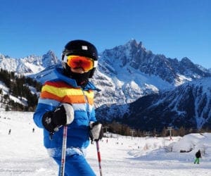A boy wearing a retro blue ski jacket skiing in the Alps.