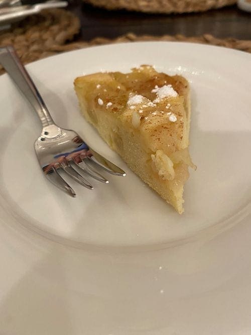 A slice of apple sharlotka on a plate, aside a fork.