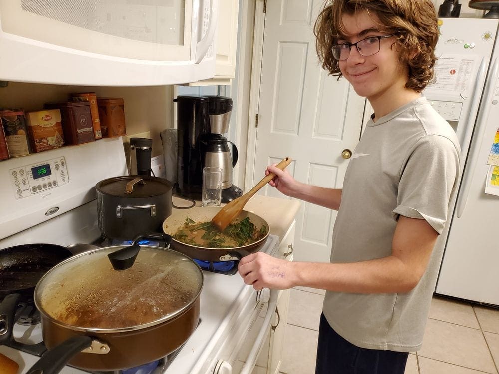 A teen boy stirs a pan of Ethopian saga tibs, one of the featured recipes from around the world.