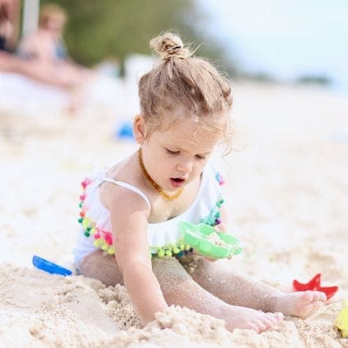 A young girl sits playing in the beach at Caribbean Club Hotel Grand Cayman.
