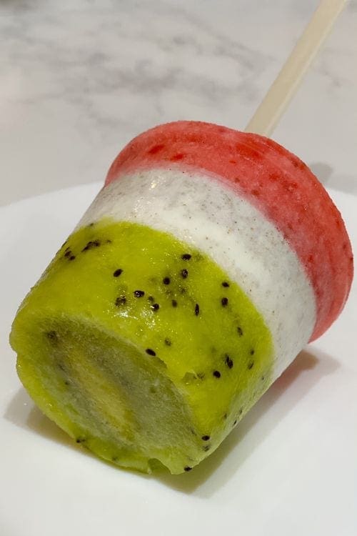 A Mexican paleta on a plate, featuring green, white, and red layers.