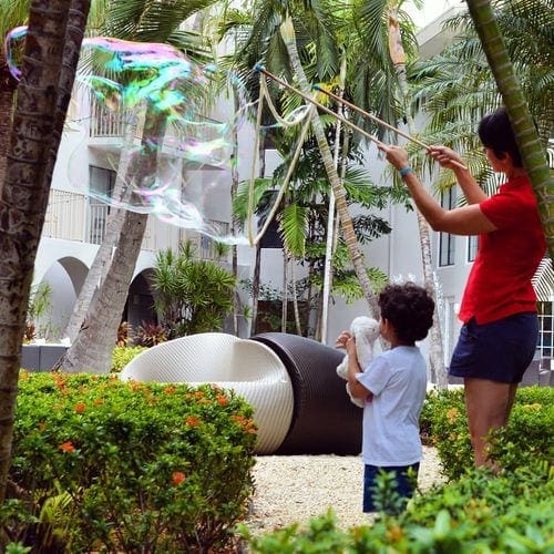 A young boy and an adult play with huge bubbles at Grand Cayman Marriott Beach Resort.