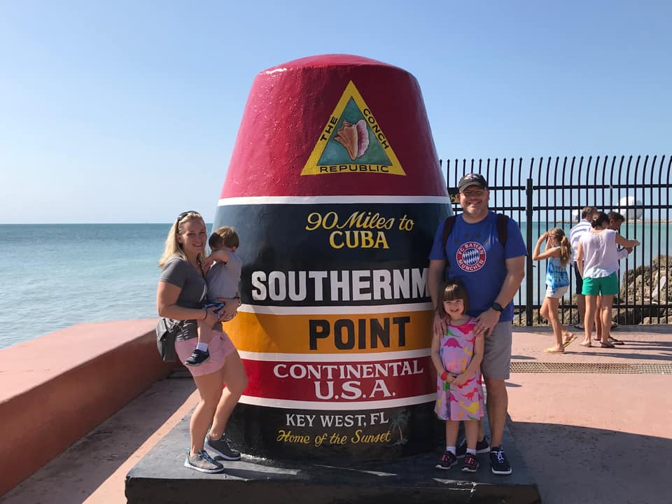 A family of four poses at the marker for the southernmost point of the continental United States.