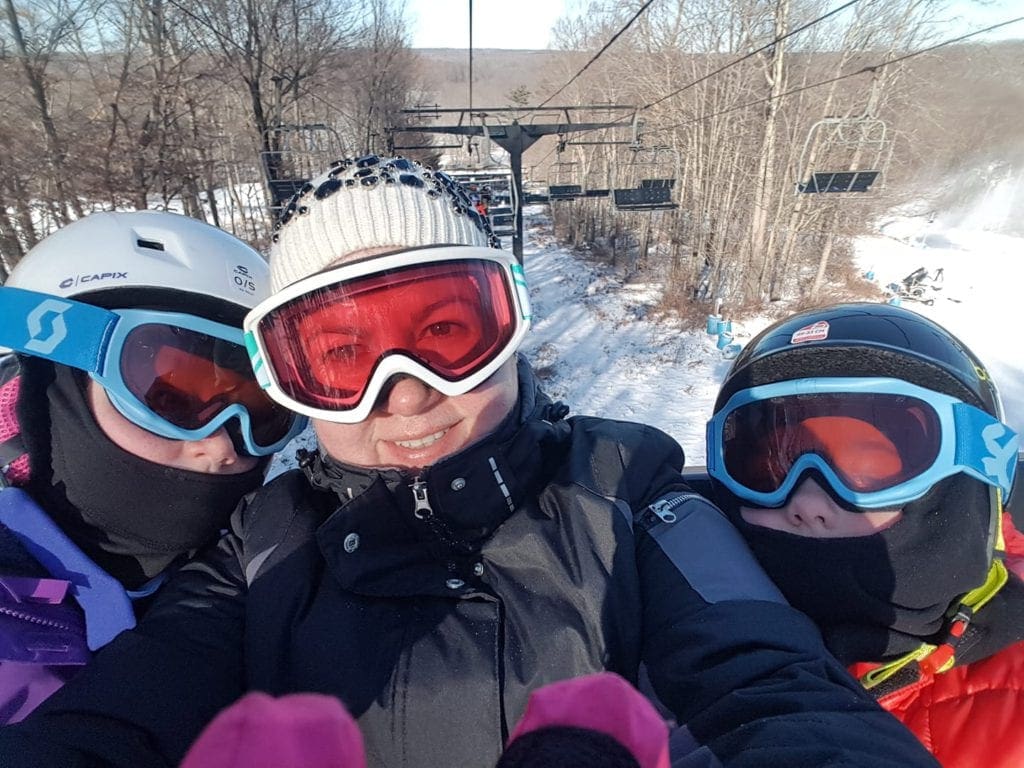 A mom and two kids take a selfie on the chair lift at Bear Creek.