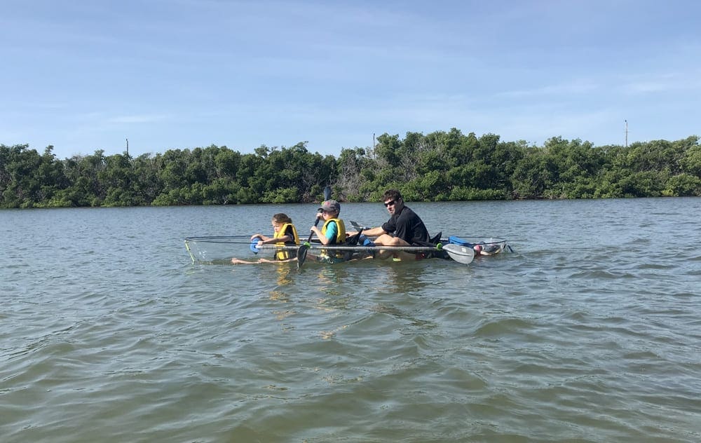A dad and his two kids canoe along a river in Key West.