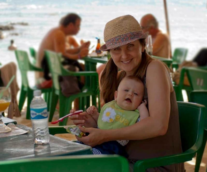 Mom holding a baby and eating in an outdoor restaurat in Playa del Carmen