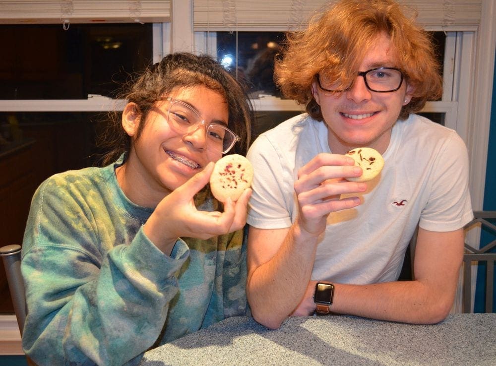Two teenagers smile while eating indigenous cookies from the United States, one of the featured recipes from around the world.
