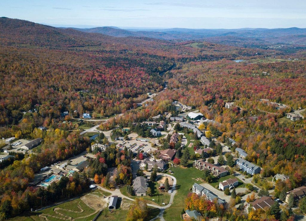 Aerial view of Smugglers’ Notch Resort during the fall, featuring birght autumn colors.
