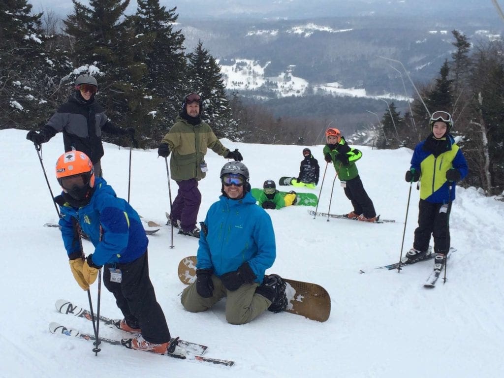 A large group of skiers rests at the top of a run at Okemo in Vermont, one of the best ski resorts in the United States for families.