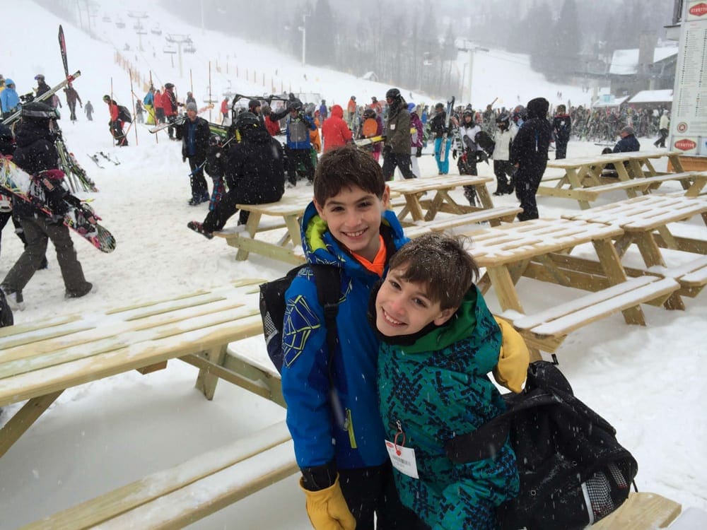 Two kids embrace near picnic tables on the grounds of Stratton Mountain Resort, one of the best family ski resorts in Vermont.