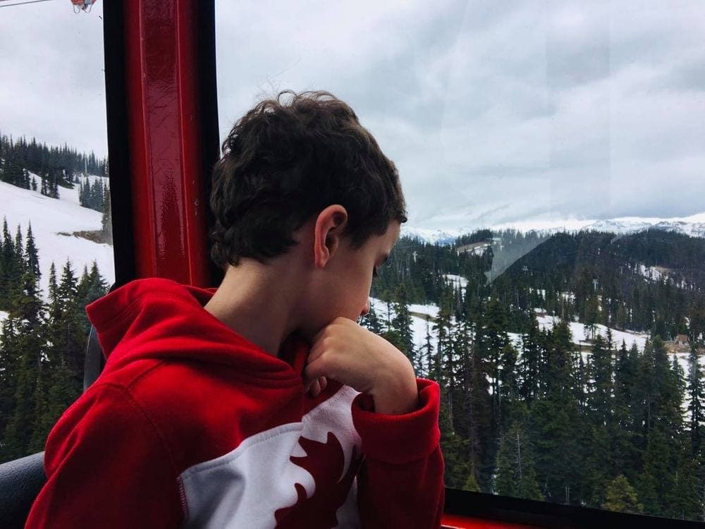 A young boy looks out the window of the Peak 2 Peak gondola in Whistler.
