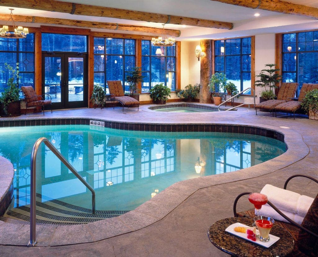 The indoor pool at Whiteface Lodge, featuring large windows and comfy seating.
