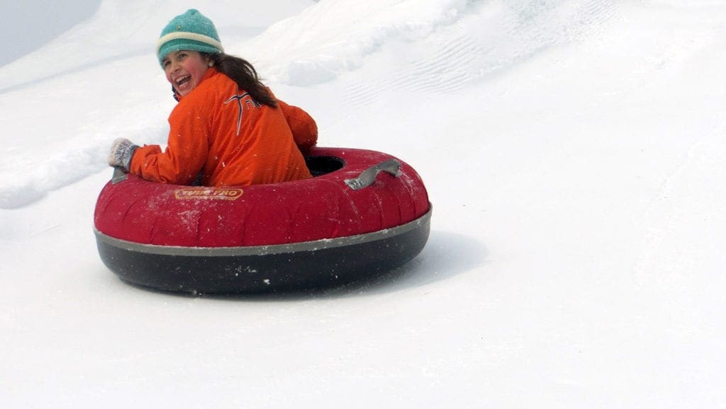 A girl rides down a snowy hill on a snow tube at Omni Mt. Washington.