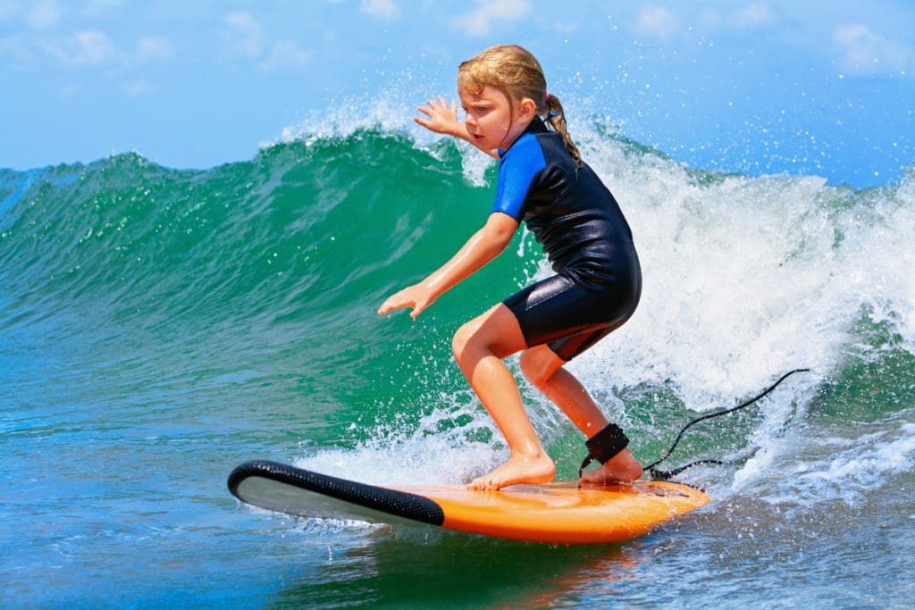 A young girl surfs a wave off-shore from Los Cabos.