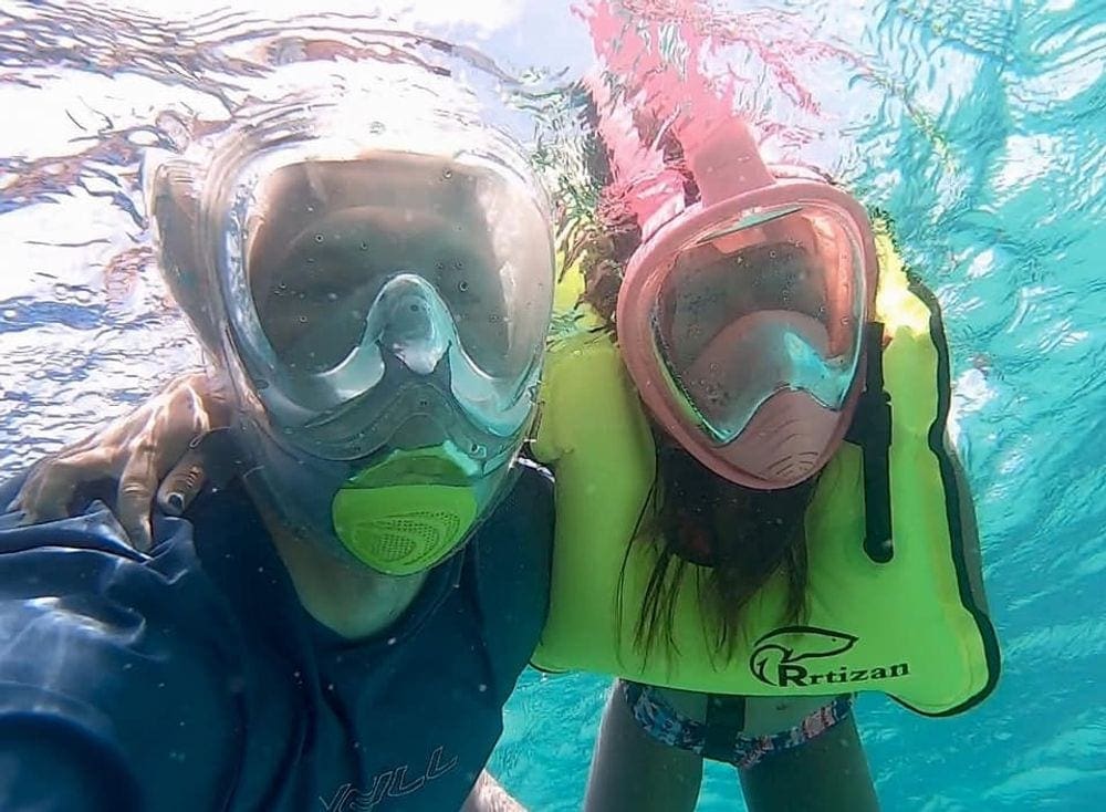 A parent and child pose underwater while snorkeling in Turks & Caicos.