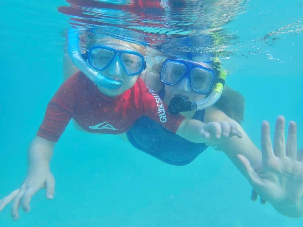 A mom and child snorkel underwater at Dry Tortugas National Park wearing snorkel masks, an important component to kids snorkel gear.