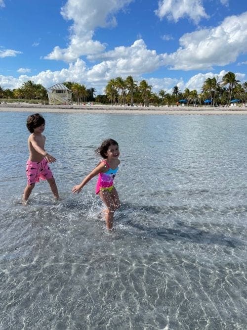 Two kids run and play in the water off-shore on Key Biscayne.
