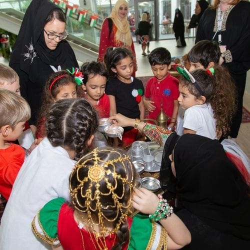 A woman holds out a tray of goodies for children to take at the Sheikh Mohammed bin Rashid Al Maktoum Centre for Cultural Understanding.