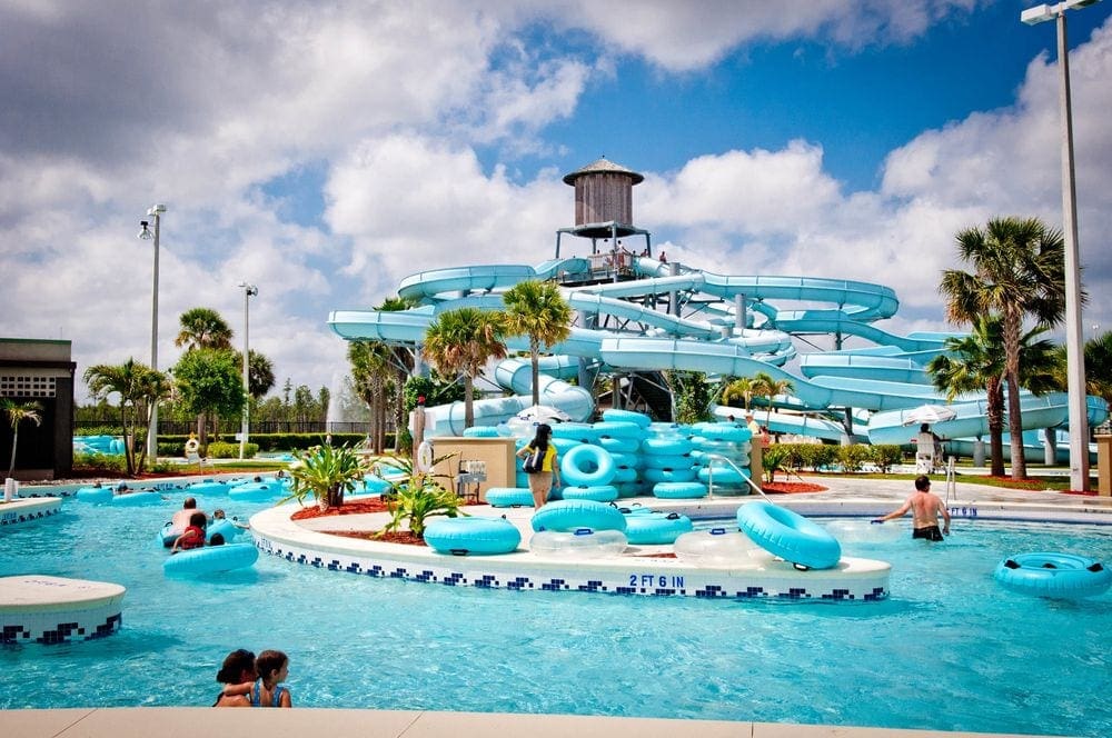 Several people enjoy large blue water tubest and water slides at the Sun-N-Fun Lagoon, Naples Waterpark on a sunny day.