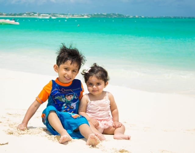 Two kids sit on the beach on the island of Turks and Caicos.