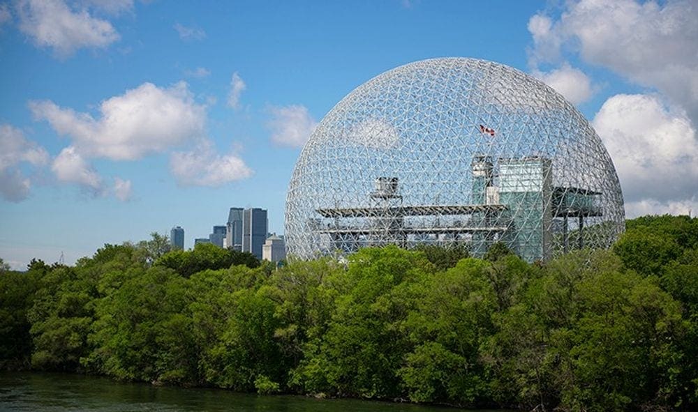 The Biosphere, Environment Museum's inconic dome beyond a lush green tree-line.