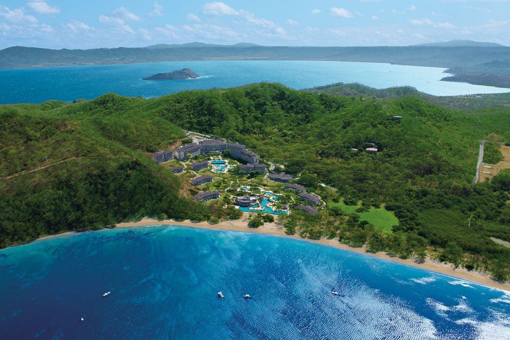An aerial view of Dreams Las Mareas Costa Rica, one of the best Costa Rica resorts for a family vacation, nestled along a rugged Costa Rican coastline.