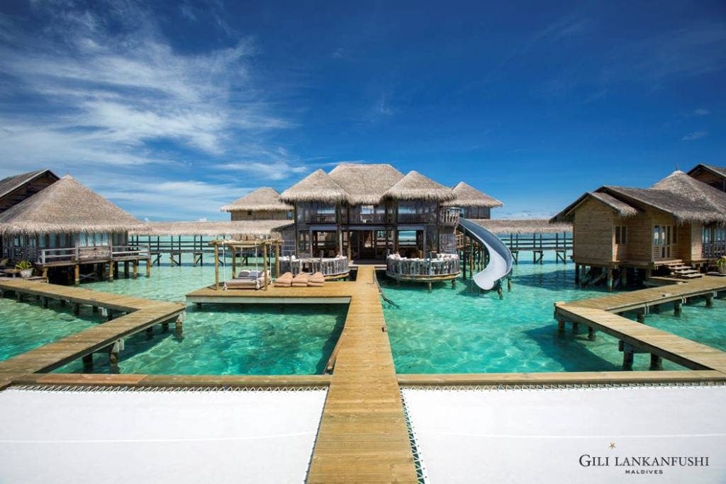 Over ocean resort buildings at the Gili Lankanfushi Maldives, featuring a slide extending from the middle building.