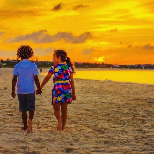 Two young kids walk hand-in-hand along the beach at Grace Bay Club.