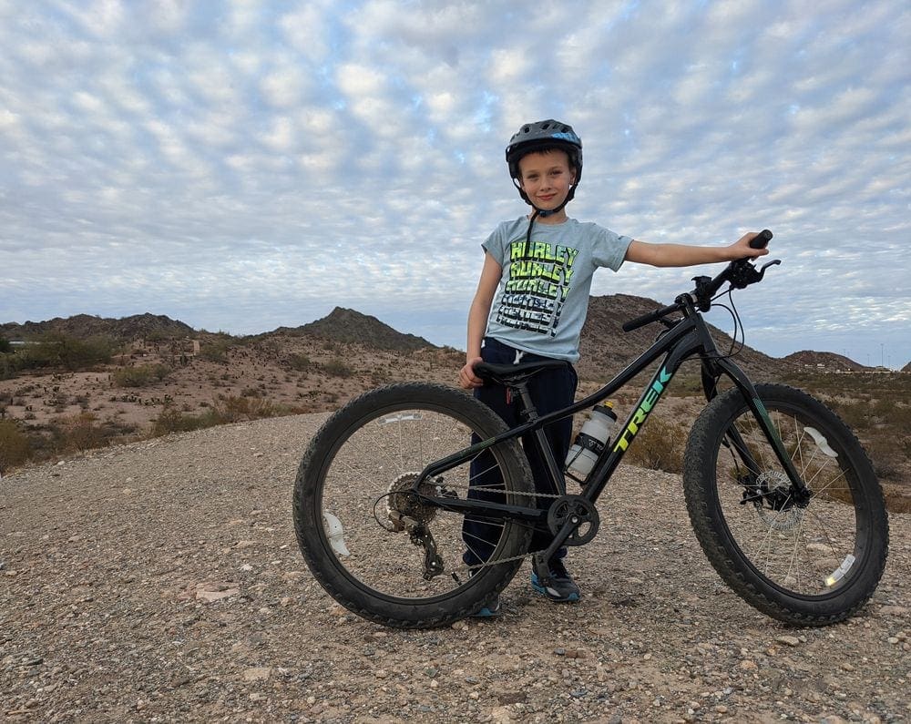 A young boy wearing a helmet poses with his bicycle on a trail at Dreamy Draw Loop.