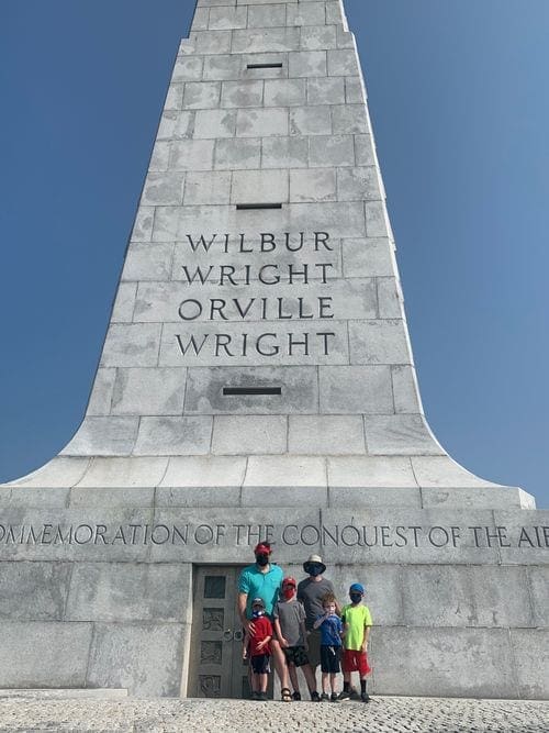 A family of five stands in front of a monument at the Wright Memorial in the Outer Banks.