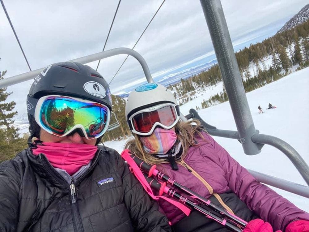 An adult and pre-teen child ride together on a ski lift in Deer Valley.