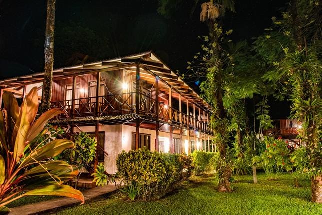 The hotel buildings surrounded by lush foliage at night at Tortuga Lodge & Gardens, one of the best Costa Rica resorts for a family vacation.