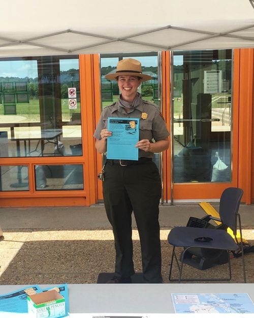 A park ranger at the Wright Brothers National Memorial holds up a paper for Junior Rangers to participate in on-site.