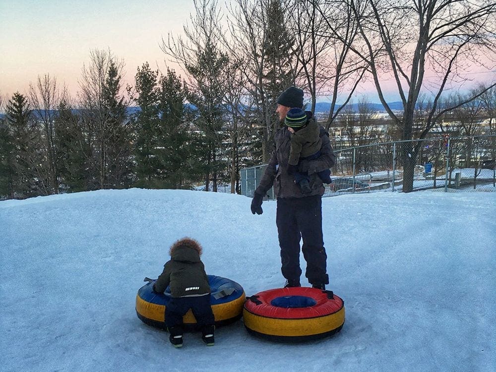 A dad and his two young kids play with snow tubes in Montreal.