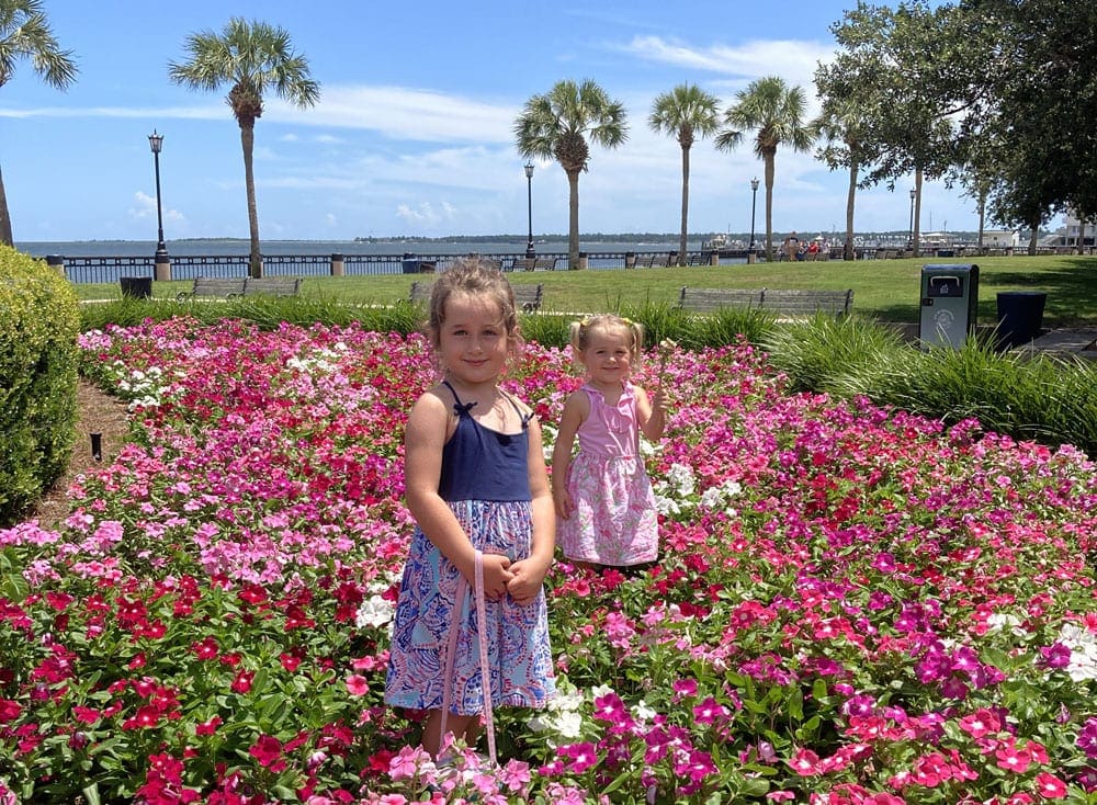 Two young girls stand in a field of flowers in Charleston, one of the best places to visit in the US during Easter Break with kids!