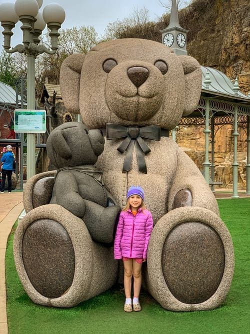 A young girl stands with a huge teddy bear in a park in Stillwater, Minnesota.