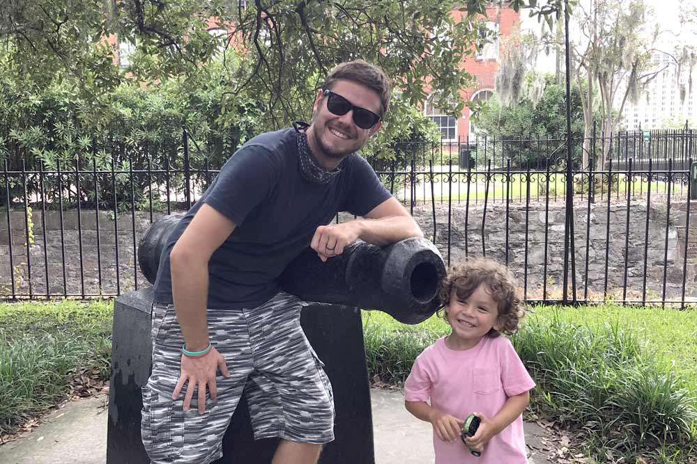 A dad and his young child while posing next to a historic cannon in Savannah.