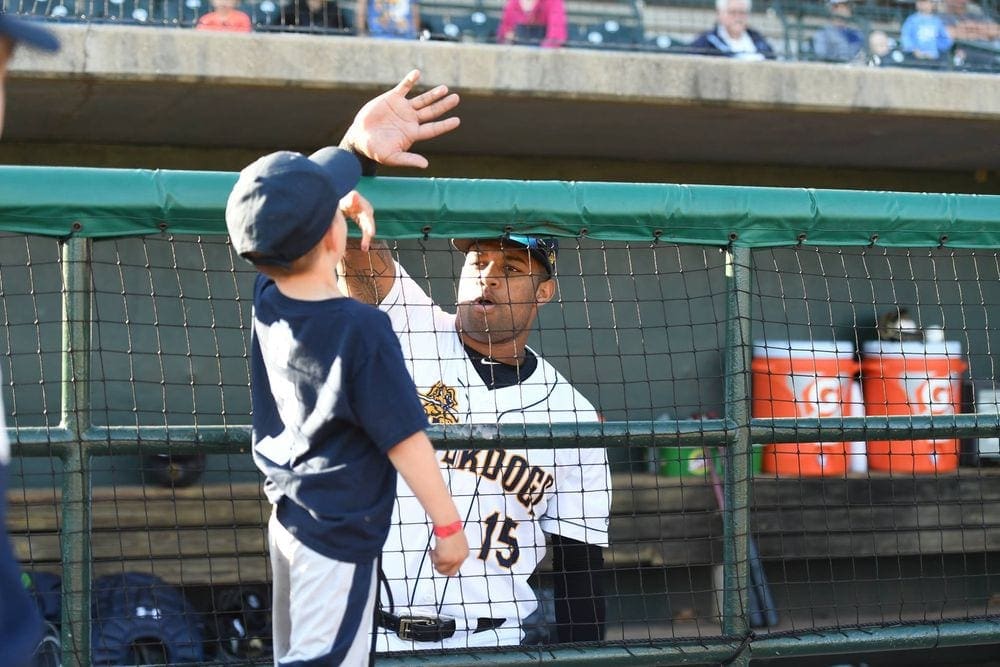 A young boy high fives a baseball player on the Charleston RiverDogs team.