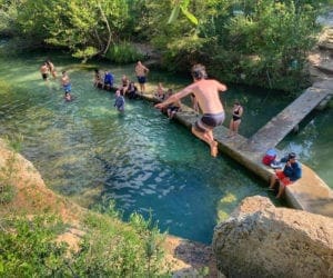 People jumping in a swimming hole in Austin -Families Love Travel