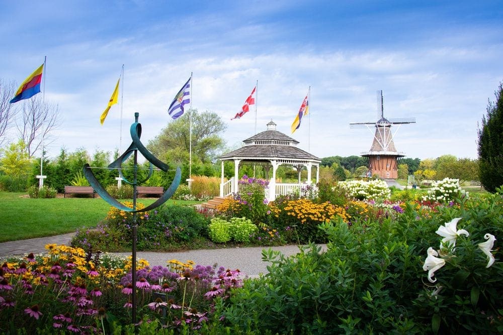 A colorful garden in Holland, Michigan, featuring a gazebo, flags. and a windmill at one of the best places to visit in Michigan with kids.