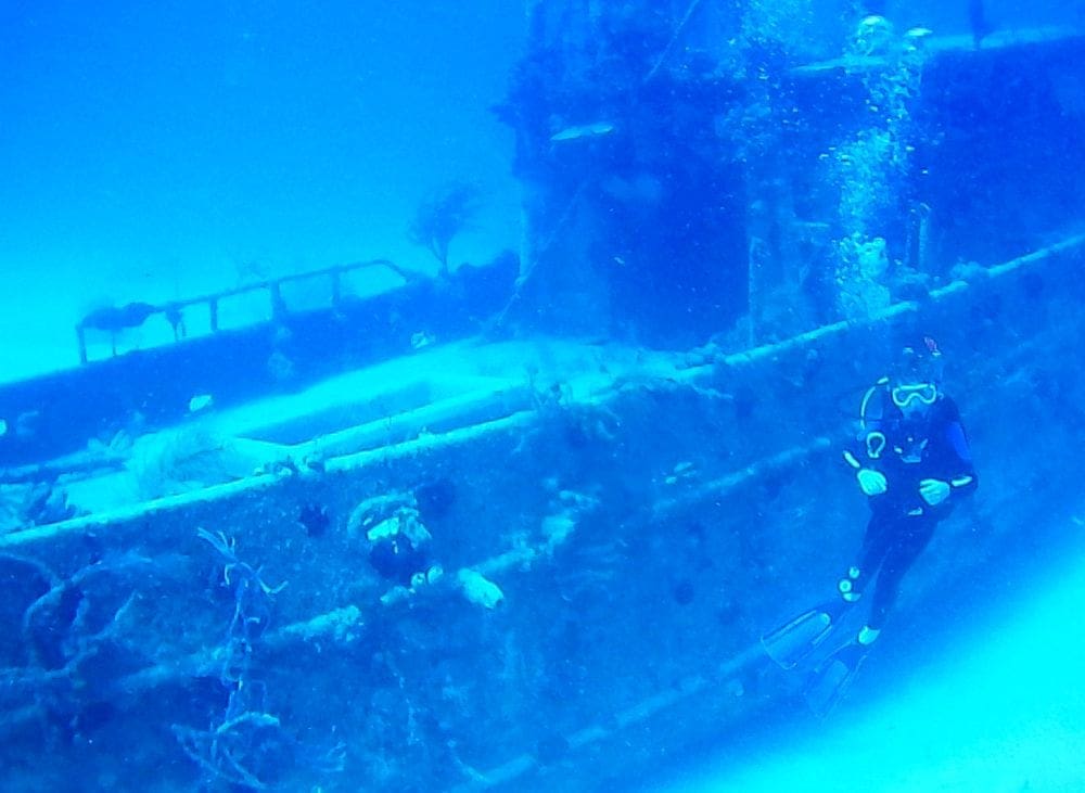 Boys in front of a tug boat ship wreck while scuba diving in the Bahamas.
