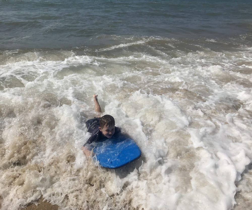 A young boy splashes in the waves on his boogie board on South Beach.