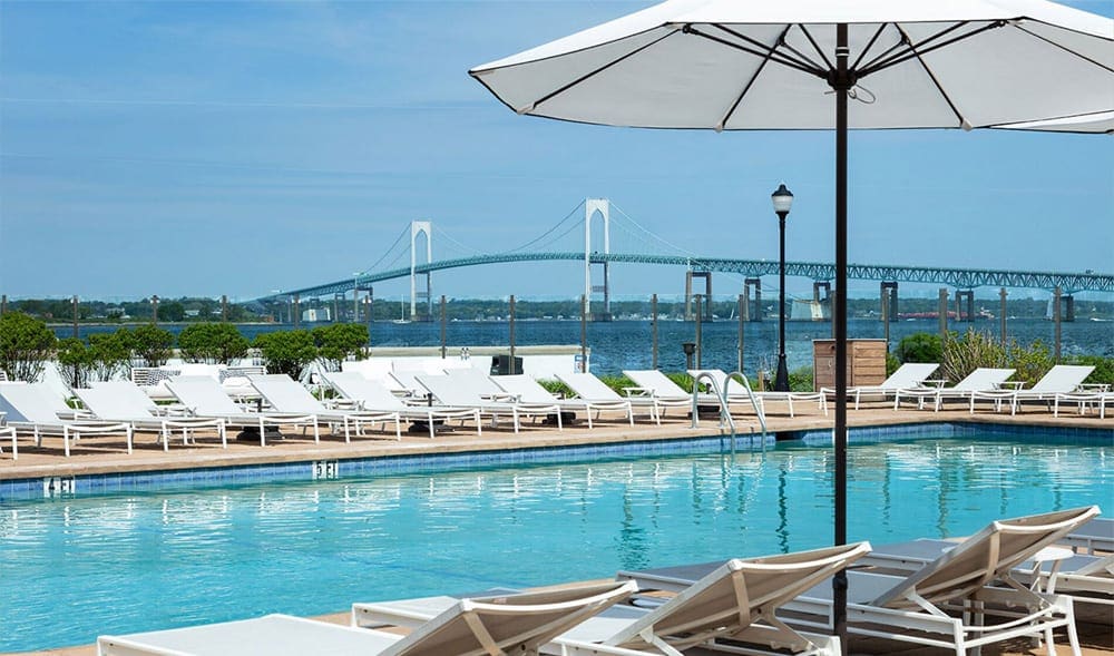 Several white loungers await guests along the outdoor pool at Gurney’s Newport Resort & Marina.