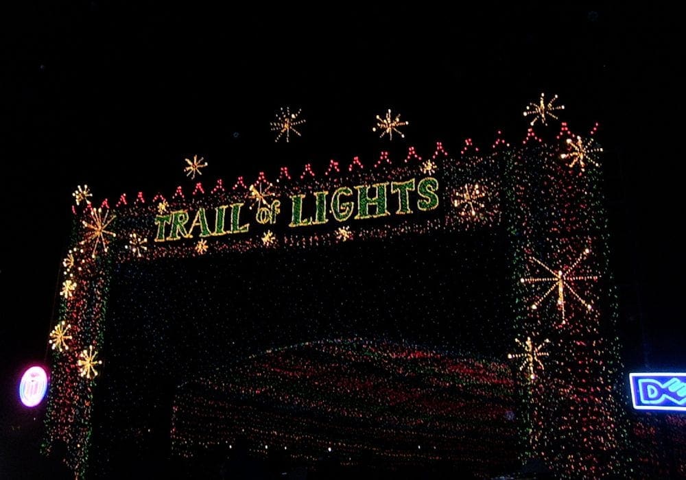 Inside the Zilker Christmas light display, featuring a lit sign that reads "Trail of Lights".