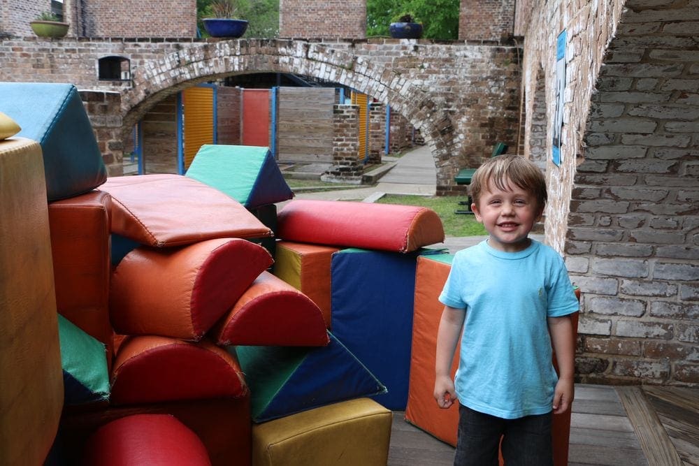 A young boy smiles while playing on large, colorful cushions at the Savannah Children's Museum.