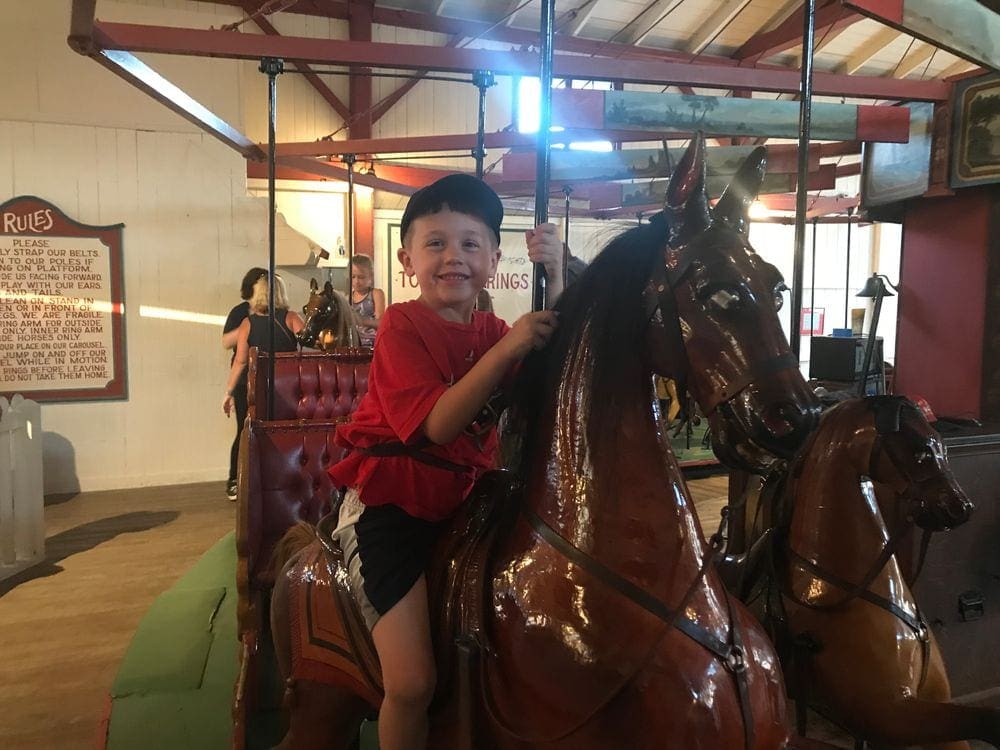 A young boy sits on a carousel horse at OB Flying Horses, one of the best things to do on your Family Vacation in Martha's Vineyard.