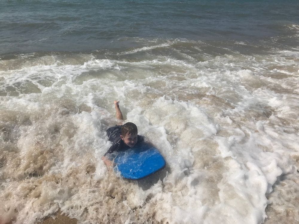 A young boy splashes in the waves on his boogie board on South Beach, one of the best things to do on your Family Vacation in Martha's Vineyard.