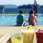 Two kids sit at the edge of a pool at The Sagamore, while their fruity drinks wait for them at the lounger.